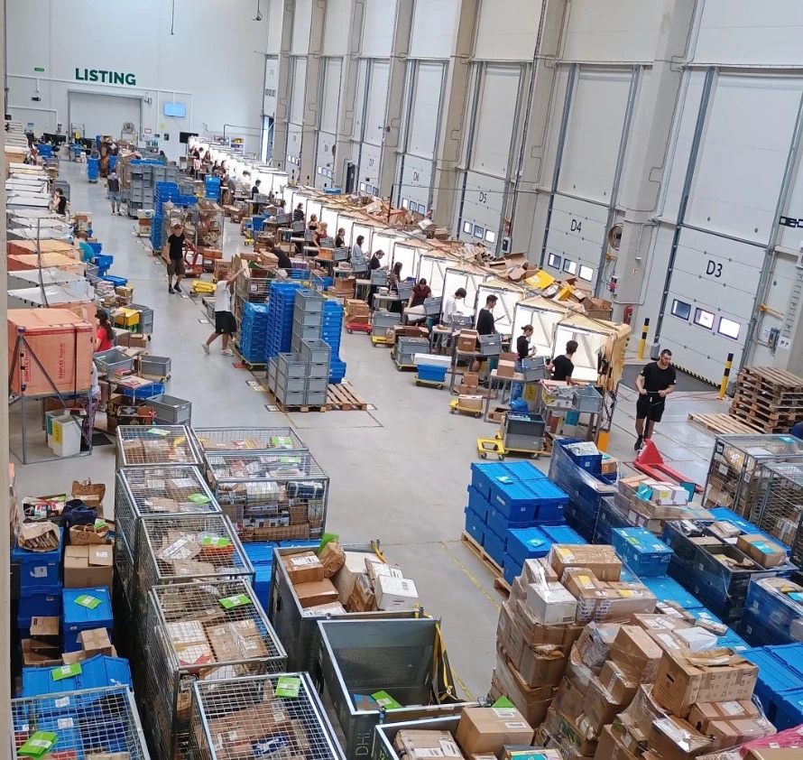 Hala logistického centra s listingem plná lidí a beden s knihami